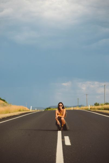 woman kneeling on asphalt road