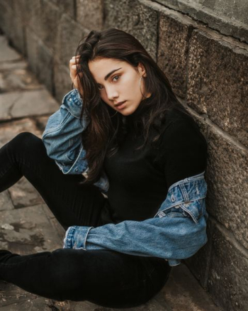 woman leaning on brown concrete wall