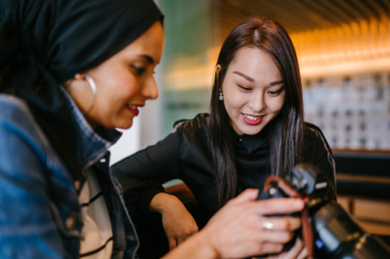 Woman Looking to Woman Holding Dslr Camera