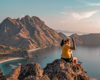 Woman Making Peace Hand Sign While Sitting on Rock Boulder Woman Making Peace Hand Sign While Sitting on Rock Boulder