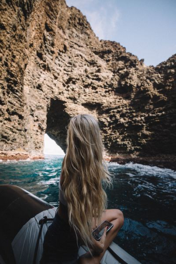 woman on black and white boat looking on brown rock formation during daytime