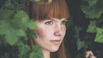 woman peeking between green leafed plants