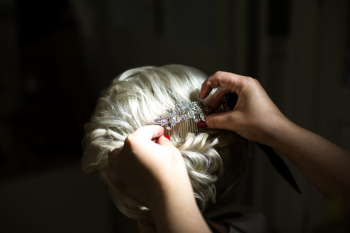 Woman puts crystal hairpin in bride's blonde hair Woman puts crystal hairpin in bride's blonde hair
