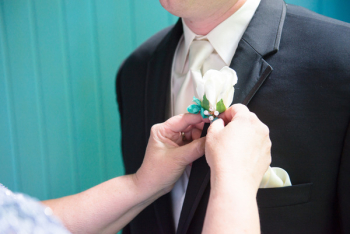 Woman Putting Boutonniere On Man's Suit Woman Putting Boutonniere On Man's Suit
