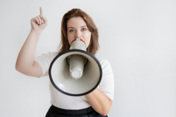 Woman raising index finger when speaking loudly in megaphone Woman raising index finger when speaking loudly in megaphone