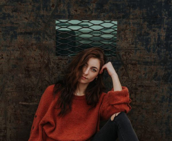 woman resting her head on left arm leaning on brown wall