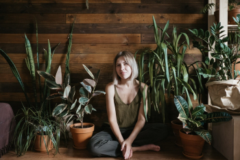Woman Sits on the Floor Between Indoor Plants Woman Sits on the Floor Between Indoor Plants