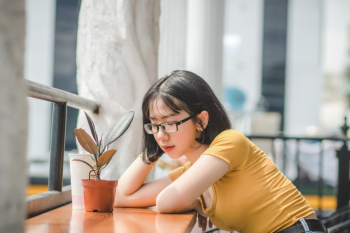 Woman Sitting Beside Table With Plant Woman Sitting Beside Table With Plant