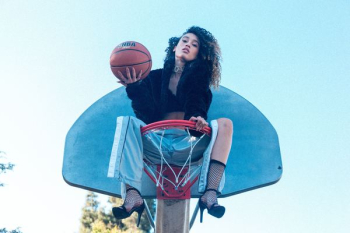 woman sitting on basketball hoop holding basketball at daytime woman sitting on basketball hoop holding basketball at daytime
