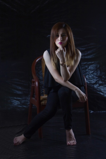 Woman Sitting on Brown Chair With Black Background Woman Sitting on Brown Chair With Black Background