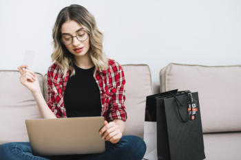 Woman sitting on couch studying sales on black friday Free Photo