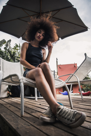 Woman Sitting on Lounger Under Umbrella Woman Sitting on Lounger Under Umbrella