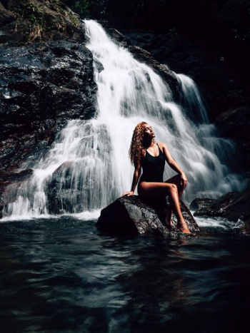 woman sitting on rock near waterfalls