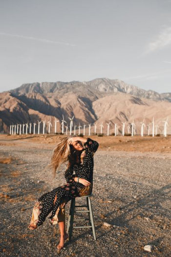 woman sitting on wooden bar stool near white wind turbines