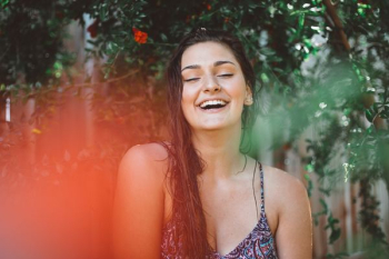 woman smiling under green tree