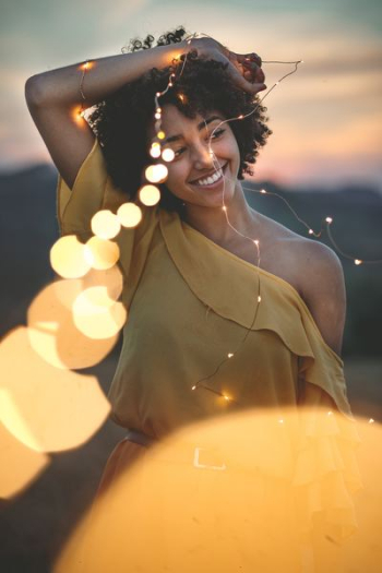 woman smiling while holding string lights