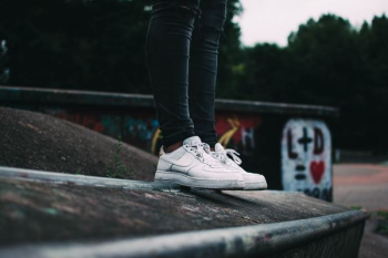 woman standing and wearing white Nike low-top sneakers woman standing and wearing white Nike low-top sneakers