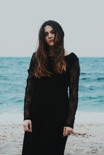 woman standing on gray sand near the ocean during daytime