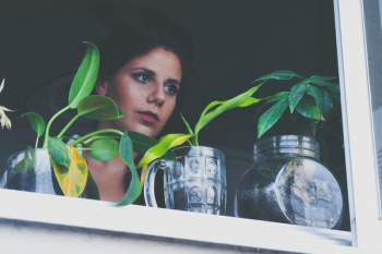 woman standing on near windowpane with glass flower vases woman standing on near windowpane with glass flower vases