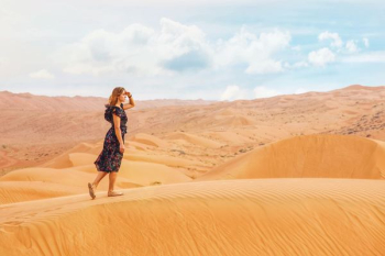 woman walking on sand dunes during daytime woman walking on sand dunes during daytime
