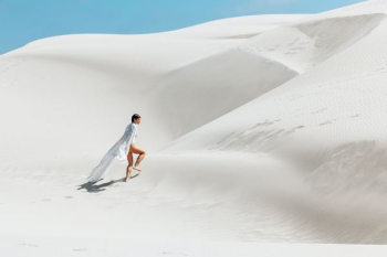 woman walking on white sand dunes woman walking on white sand dunes