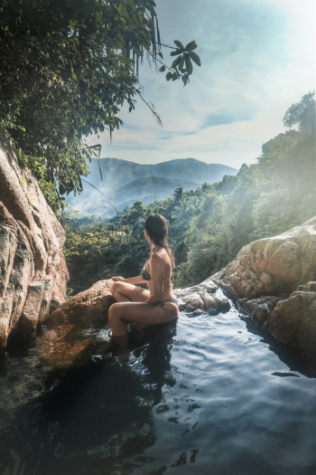 Woman Wearing Bikini Sitting on Rock Formation Near Trees Woman Wearing Bikini Sitting on Rock Formation Near Trees