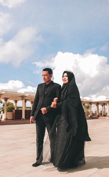 Woman Wearing Black Hijab Holding Man in Black Suit Woman Wearing Black Hijab Holding Man in Black Suit