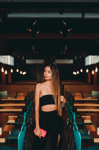 Woman Wearing Black Tube Top Standing In Between Tables and Chairs Woman Wearing Black Tube Top Standing In Between Tables and Chairs