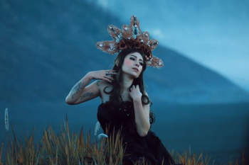 woman wearing black tube top with brown and white headdress standing in field