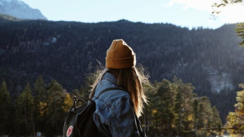 woman wearing blue denim jacket overlooking green forest