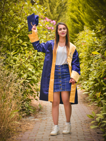 Woman Wearing Blue Graduation Gown raising Graduation Cap Woman Wearing Blue Graduation Gown raising Graduation Cap