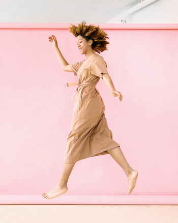 Woman Wearing Brown Dress Jump Near Pink Wall