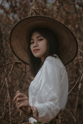 woman wearing conical hat surrounded by trees woman wearing conical hat surrounded by trees