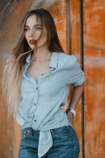 woman wearing dress shirt holding her gray denim bottom pocket