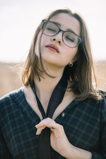 Woman Wearing Eyeglasses Touching Her Necktie Woman Wearing Eyeglasses Touching Her Necktie