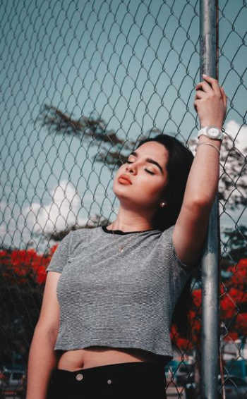 woman wearing gray crew-neck crop top holding gray fence