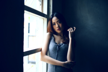 Woman Wearing Gray Sleeveless Dress Leaning on Clear Glass Window