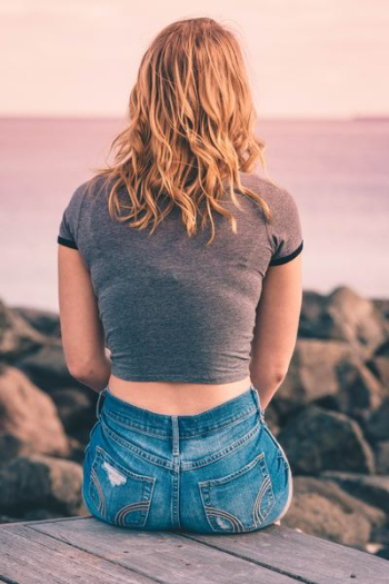 woman wearing gray top sitting in front of sea woman wearing gray top sitting in front of sea