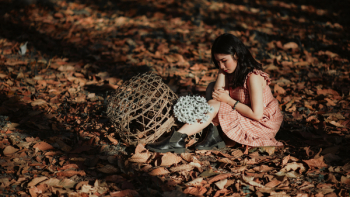 Woman Wearing Red Dress Sitting on Brown Ground With Woven Brown Basket