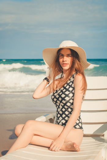 Woman Wearing Sun Hat While Sitting on Sun Lounger Woman Wearing Sun Hat While Sitting on Sun Lounger
