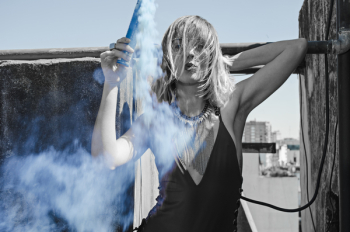 Woman With Halter-strap Top and Layer Necklace Holds Black Tube With Smoke