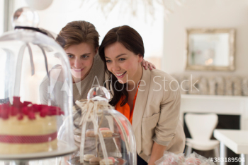 Women friends eyeing desserts in bakery Women friends eyeing desserts in bakery
