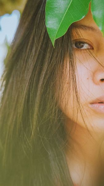 women's face under green leaf