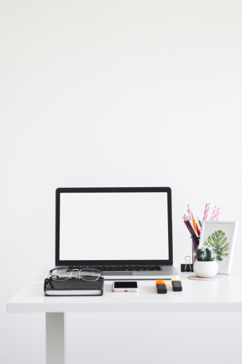 Workplace with laptop near eyeglasses, notebook, markers and mobile phone