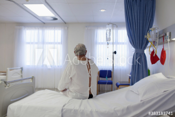 Worried male senior patient sitting on edge of hospital bed Worried male senior patient sitting on edge of hospital bed
