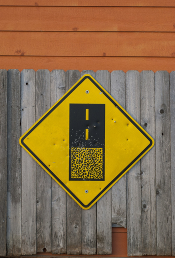 Yellow and Black Road Sign on Gray Wooden Fence Yellow and Black Road Sign on Gray Wooden Fence