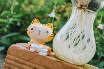 Yellow Cat Figurine Beside Clear Glass Vase Yellow Cat Figurine Beside Clear Glass Vase