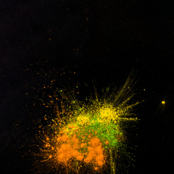 Yellow,green and orange colored powder splatted over black backdrop