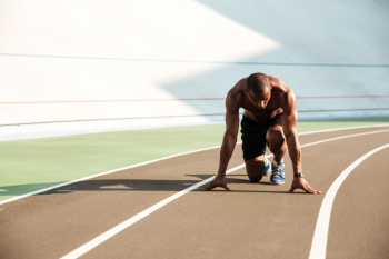 Young afro american sports man in starting position ready to start on sports track at the stadium Free Photo