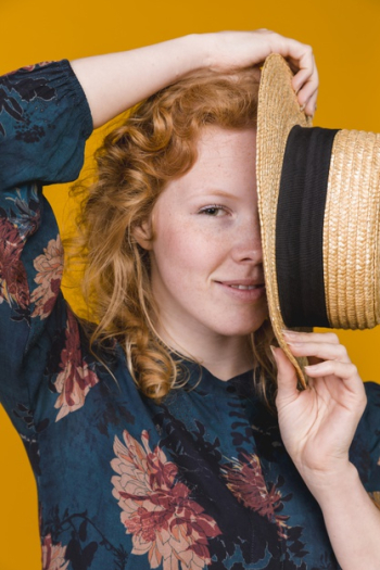 Young attractive woman hiding half of face with hat Free Photo